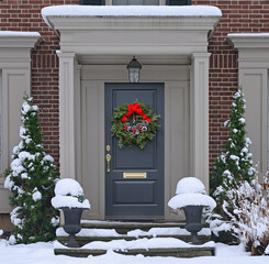 Front door with natural pine cone Christmas wreath with snow covered steps