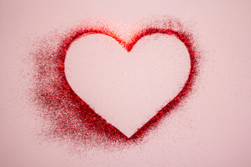 Happy Valentine's Day. Red heart made of glitter on a pastel pink background