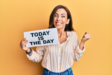 Fototapeta na wymiar Young brunette woman holding today is the day screaming proud, celebrating victory and success very excited with raised arm