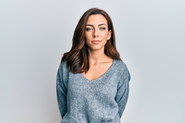 Young brunette woman wearing casual winter sweater relaxed with serious expression on face. simple...