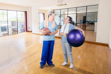 Happy old couple holds basketball and pilates ball