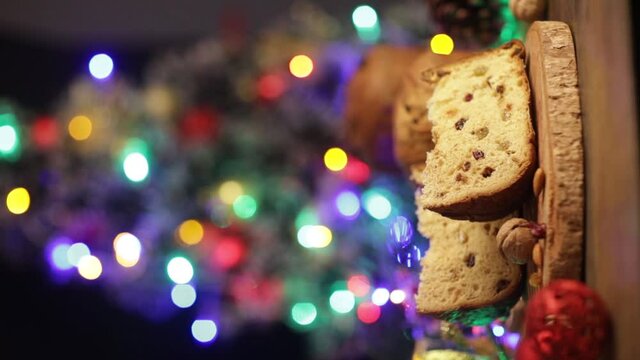Delicious slice of Panettone with candied fruit on the table on a blurred background.