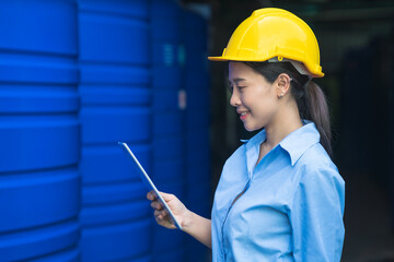 industrial factory worker with yellow hardhat standing and holding tablet