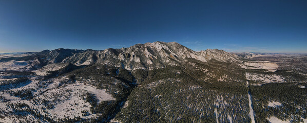 Snow capped foothill mountains panorama with blue sky and pine trees in Colorado