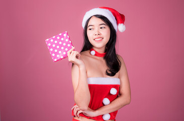 Portrait of cute Asian Christmas Santa Claus girl on pink background. Christmas and new year concept.