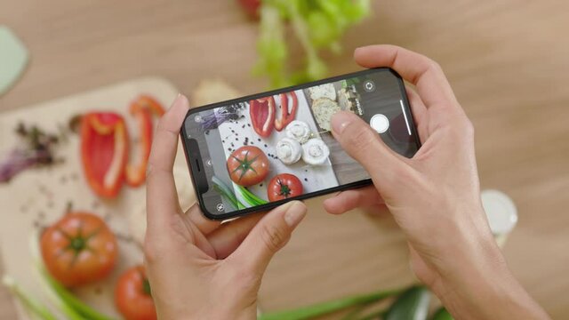 Hands woman taking a picture of board with vegetables on wooden table. Top view food photo. Vegan blogging lunch blogger. Slow motion