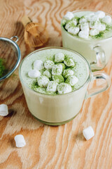 Homemade warm Matcha latte, green tea with coconut milk and marshmallow on wooden background.