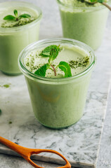 Raw vegan dessert. Matcha green tea chia seed pudding with fresh mint and coconut milk on a gray stone background.
