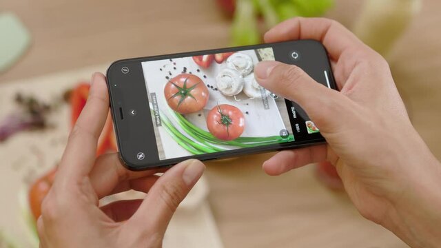 Top view of woman hands taking a picture of board with vegetables on wooden table. Food photo. Vegan blogging lunch blogger. Slow motion