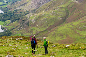 Fototapeta na wymiar Senior hikers in Lake District looking at Buttermere lake from Haystacks peak