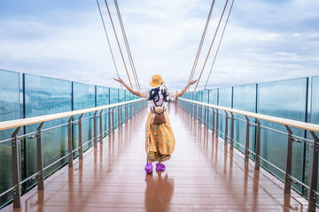Traveller woman standing on Ai Yerweng Skywalk in Yala province, the longest skywalk in Asia. Tourists visit the landmark above forest during sunrise.