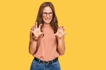 Young hispanic woman wearing casual clothes and glasses smiling funny doing claw gesture as cat,...