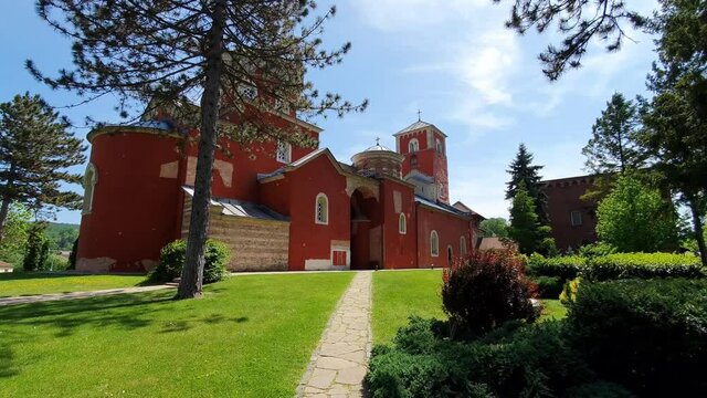 Zica Monastery, Kraljevo, Serbia. Red Orthodox Landmark, Green Garden Under Blue Sky on Sunny Summer Day