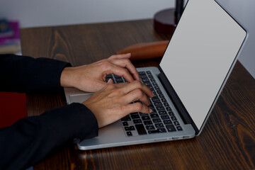 manos de chica escribiendo en teclado de un ordenador portátil, sobre un escritorio de madera. Concepto de home office.