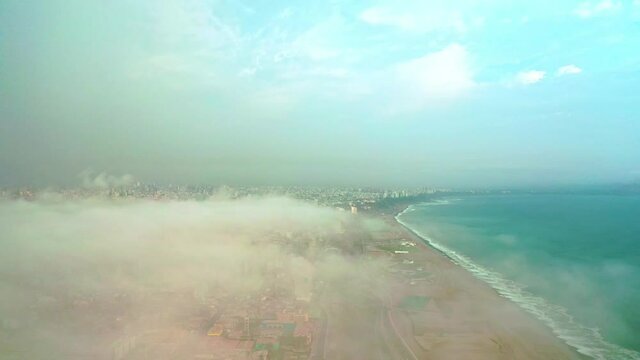 Aerial view of Lima between the clouds, view flying over the tops of the clouds and unveiling the city.
