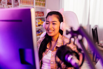 Excited and smiling gamer girl in cute headset with a mic playing an online video game and live...
