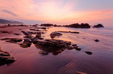 Fototapeta na wymiar Sunrise scenery of a beautiful rocky beach on northern coast of Taiwan with an island on distant horizon under dramatic dawning sky & golden sunlight reflecting on the seawater (Long Exposure Effect)