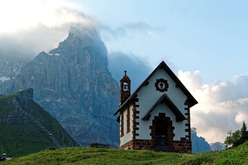 Morning scenery of a lovely chapel at the foothills of rugged mountain peaks ( Cimon della Pala ) under dramatic dawning sky in Passo Rolle, Dolomiti, Trentino Alto Adige, South Tyrol, Italy, Europe