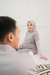 Obraz premium Portrait of a happy family in piyama clothes. A pregnant wife husband in the background