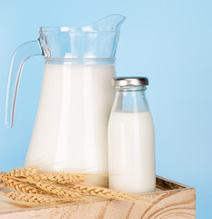 Bottle milk for a drink on a wooden crate box..Jug of fresh milk and glass on a blue background..Milk consumption nutritious and healthy dairy products concept.
