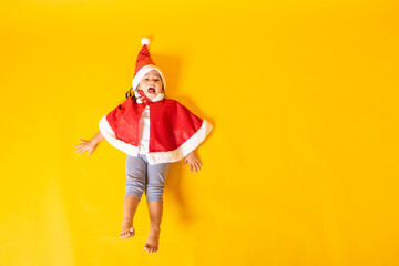 Fototapeta na wymiar Asian little cute child girl smile, Top view of a kid dressed in red Santa Claus hat the concept of holiday Christmas Xmas day or Happy new year, isolated lying on yellow background
