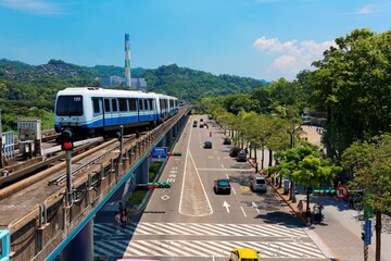 View of a train traveling on elevated rails of Taipei Metro System in suburban area under blue...
