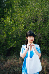 Fototapeta premium Asian woman wear blue dress with white canvas bag in nature.