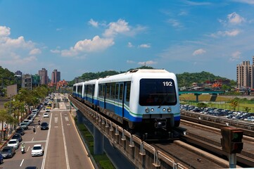 View of a train traveling on elevated rails of Taipei Metro System in suburban area under blue clear sky ~ View of railways in Mucha, Taipei, the capital city of Taiwan, on a beautiful sunny day