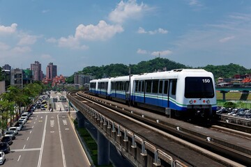 Fototapeta na wymiar View of a train traveling on elevated rails of Taipei Metro System in suburban area under blue clear sky ~ View of railways in Mucha, Taipei, the capital city of Taiwan, on a beautiful sunny day