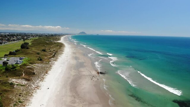 Papamoa Beach aerial pull back, Mount Maunganui on horizon, beautiful summer sunny day, New Zealand
