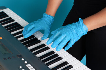 close-up of female hands and fingers in rubber medical gloves playing a melody on an electronic...