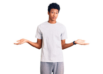Young african american man wearing casual clothes clueless and confused expression with arms and...