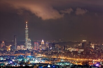 Night scenery of Downtown Taipei, the vibrant capital city of Taiwan, with view of Taipei 101 Tower standing among high-rise buildings in Xinyi Financial District and city lights dazzling in the dark