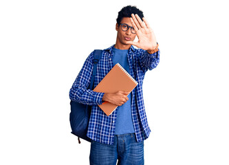 Young african american man wearing student backpack holding book doing stop sing with palm of the hand. warning expression with negative and serious gesture on the face.