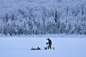 An ice fisherman enjoys the solitude of a winter day on a frozen Alaska lake.