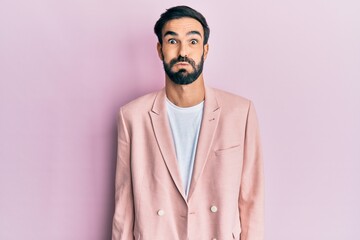 Young hispanic man wearing business jacket puffing cheeks with funny face. mouth inflated with air,...