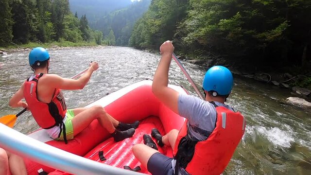 People sit in an inflatable rubber boat and float down the mountain river