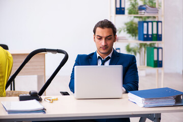 Young male employee looking after kid at workplace