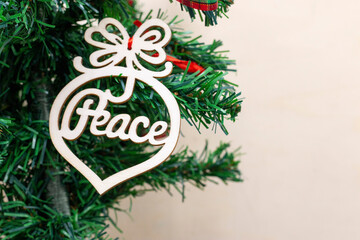 Peace word ornament is hanging on Christmas tree