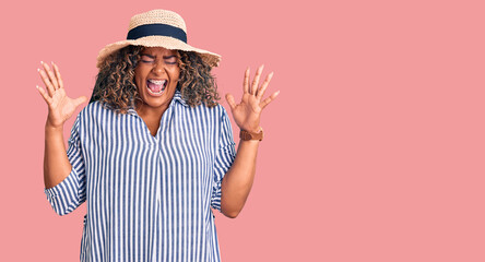 Young african american plus size woman wearing summer hat celebrating mad and crazy for success with arms raised and closed eyes screaming excited. winner concept