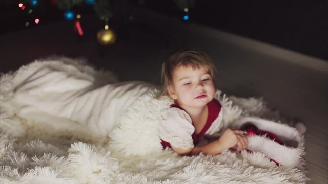 a child in red clothes is sitting waiting for the new year. the concept of celebrating Christmas at midnight. holiday costume