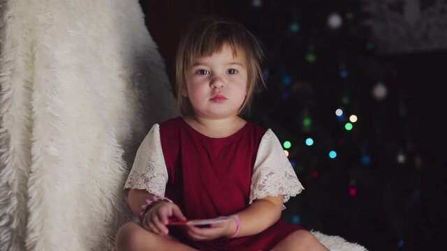 a child in red clothes is sitting waiting for the new year. the concept of celebrating Christmas at midnight. holiday costume. a girl writes a letter to Santa Claus. wish list