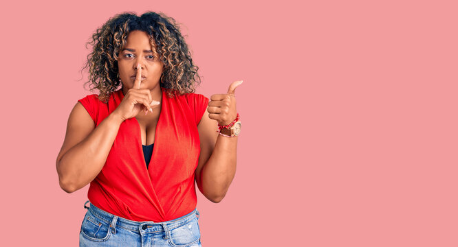 Young african american plus size woman wearing casual style with sleeveless shirt asking to be quiet with finger on lips pointing with hand to the side. silence and secret concept.