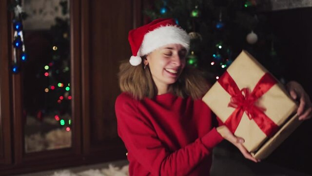 girl in red clothes unfold New year gifts. the concept of celebrating Christmas midnight. Holiday's decor boce, Christmas tree
