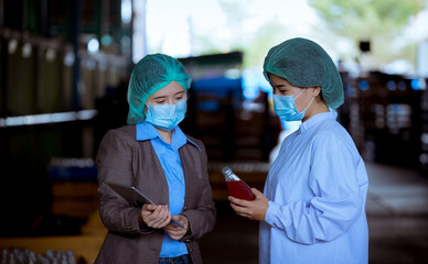 Portrait worker of science in bottle beverage factory wearing safety uniform ,face mask discussion and working to check quality of drink Basil seed produce on conveyer before distribution to market.
