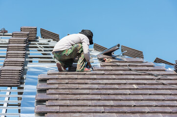 Worker man installing new roof tile on home,selective focus.