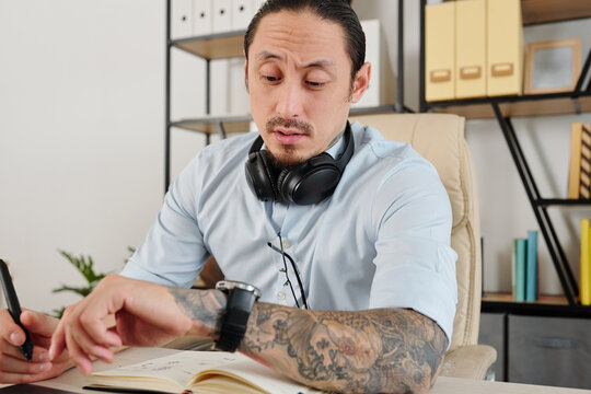 Graphic designer checking watch on his wrist after working on project for many hours