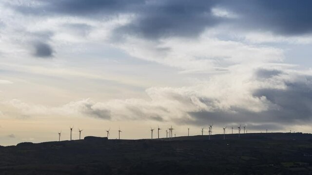 Time lapse of wind turbines in remote landscape area during daytime with passing clouds in Ireland.
