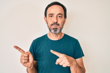 Middle age hispanic man pointing with fingers to the side puffing cheeks with funny face. mouth...