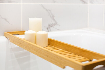 Modern bath room with wooden table and candles. White marble background wall.